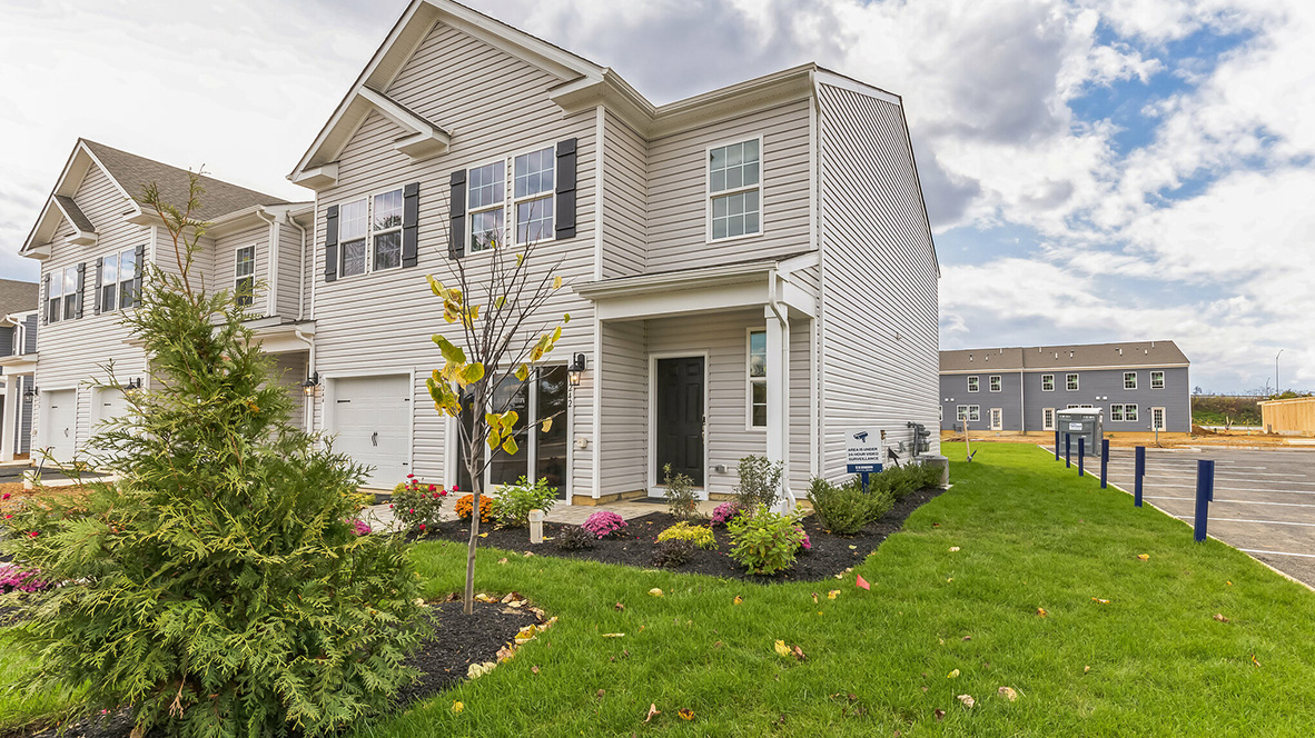 Exterior front image of the model townhome with white horizontal paneling with a white single car garage.