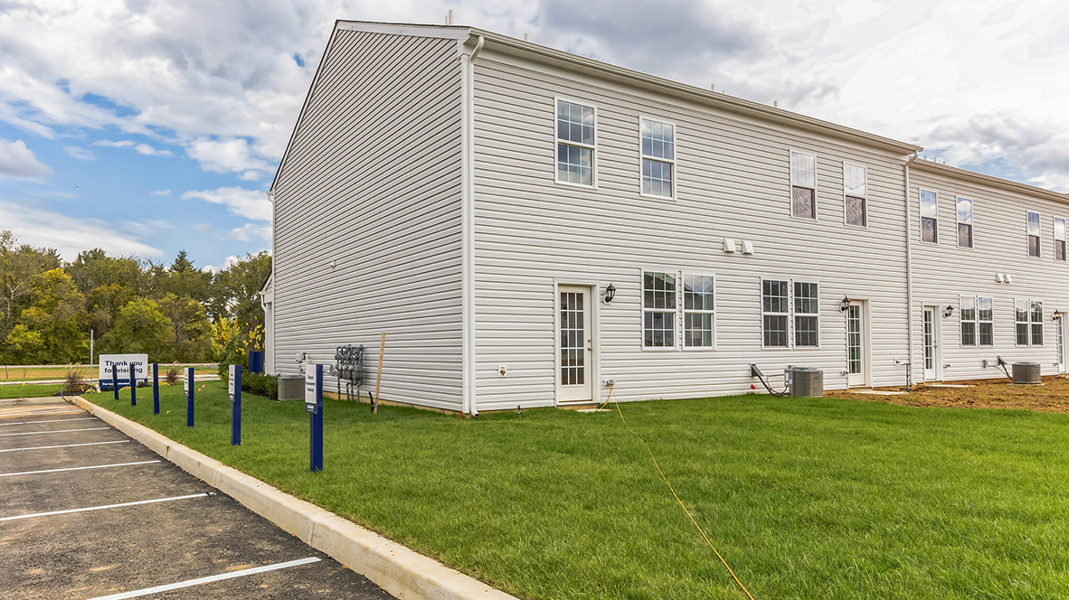 Exterior back image of the model townhome with white horizontal paneling with a back door entrance.