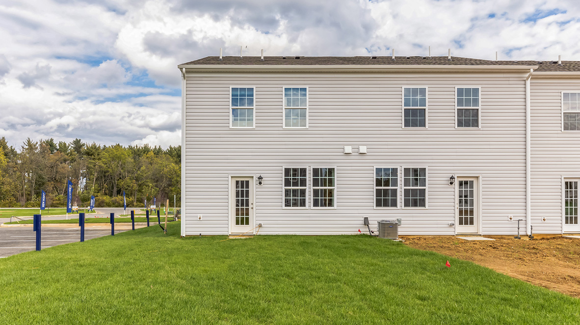 Exterior back image of the model townhome with white horizontal paneling with a back door entrance.