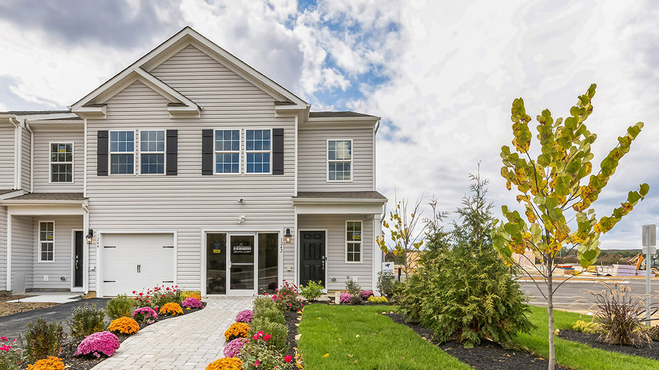 Exterior front image of the model townhome with white horizontal paneling with a white single car garage.