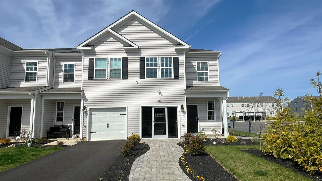 Exterior front image of the model townhome with white horizontal paneling with a white single car garage.
