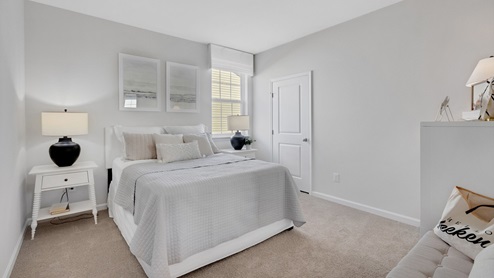 Secondary bedroom with carpet throughout and window.