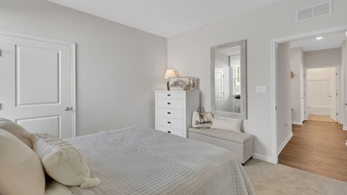 Secondary bedroom with carpet throughout and window.