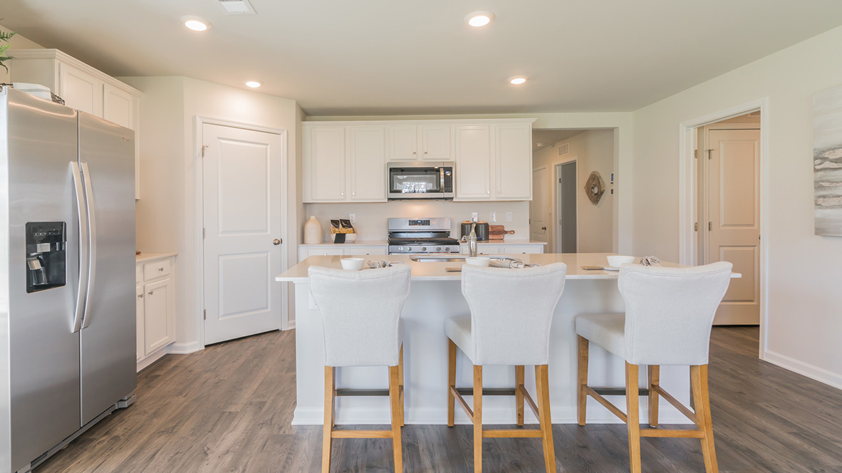 The kitchen's center island with an eat-in kitchen counter and three bar stools.