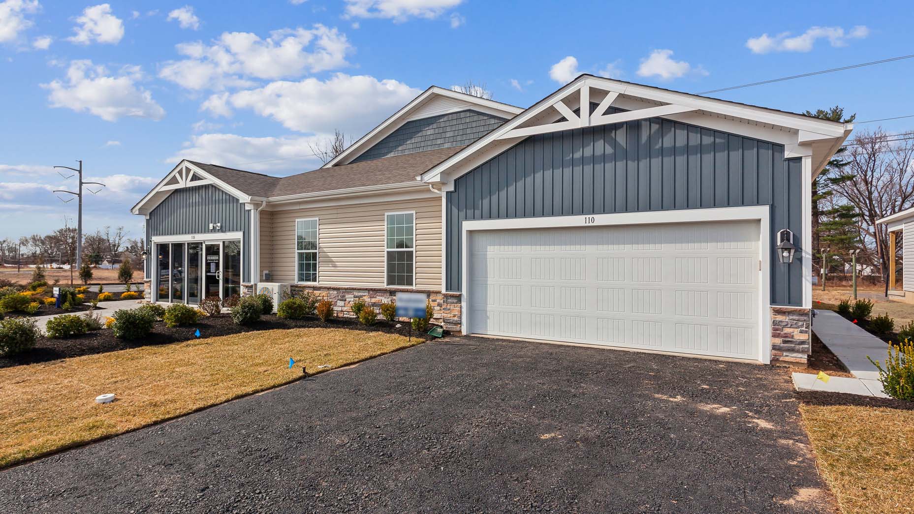 Silver Lake Reserve Burlington plan single-story twin home in wicker color siding, midnight surf board and batten accent siding, and white garage door.