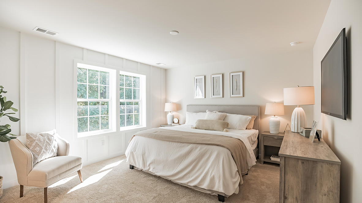 Primary bedroom on the second floor with two windows.