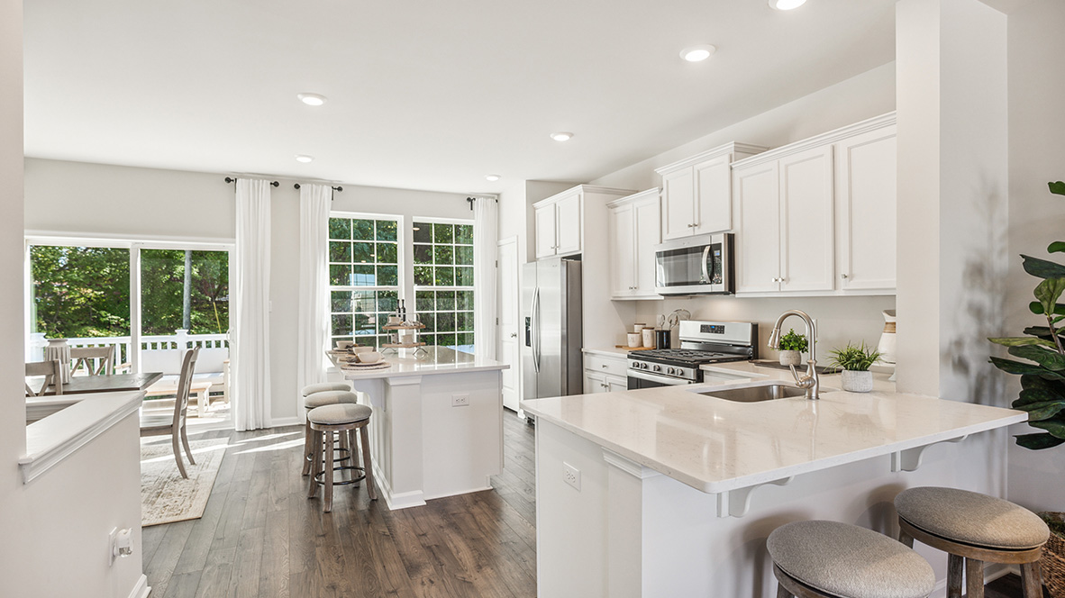 Bright white kitchen area with extra counter seating that flows into the living area.