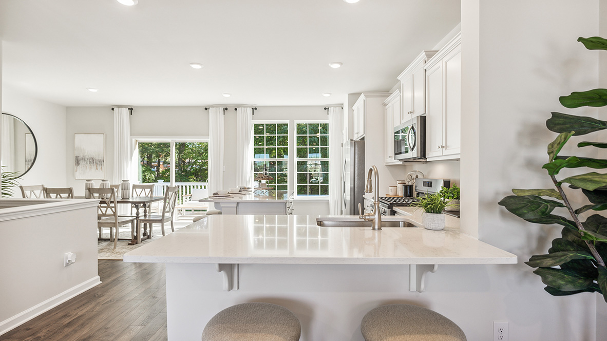 Kitchen and dining area with side counter seating in view with the back balcony door and large windows.