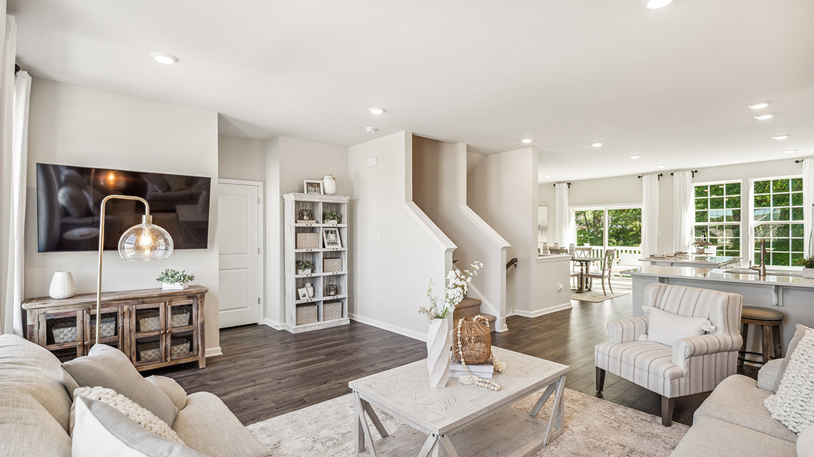 Living area with open layout view of the stairs, kitchen and dining area.