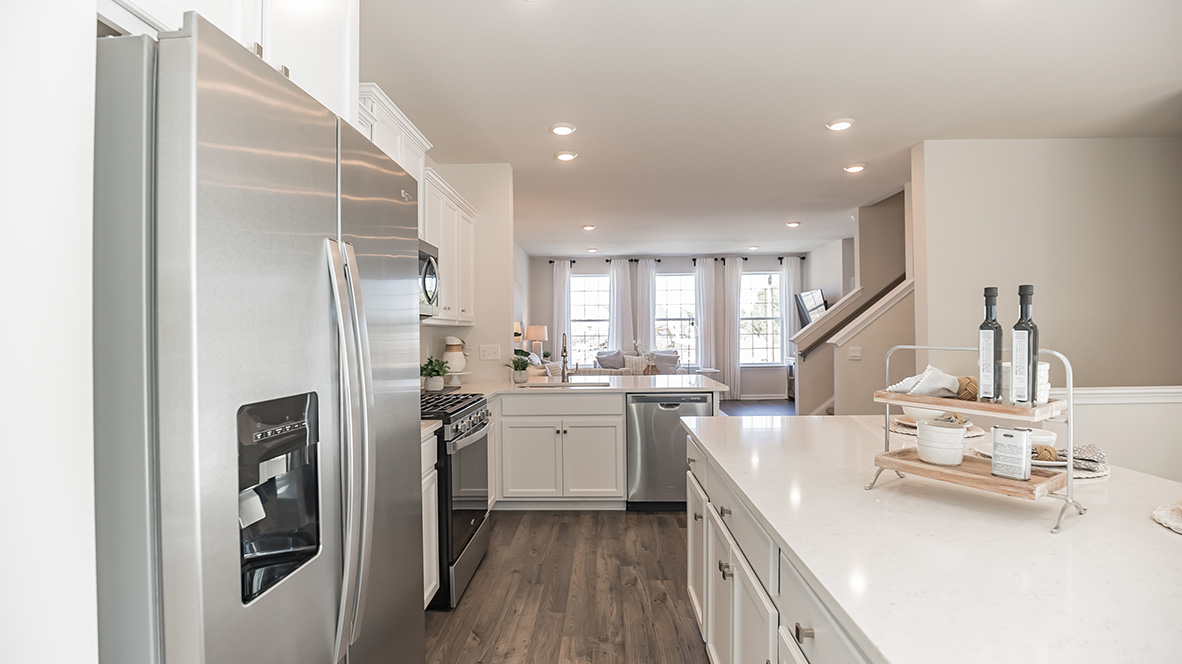 Walkway between the island and the back wall of the kitchen with a peek into the living area.