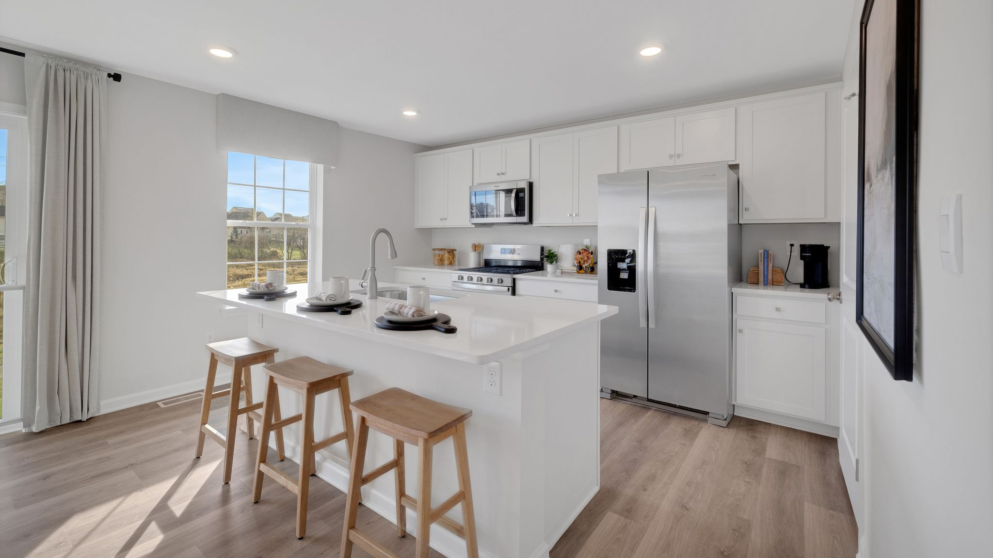 Open-concept kitchen with white cabinets and a large island.