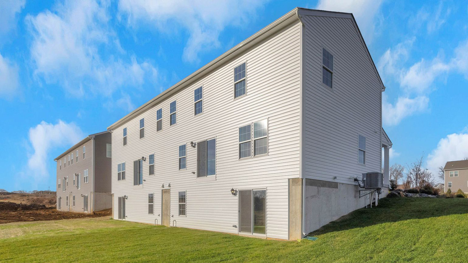 A exterior rear view of the Derby home with white siding and the walkout basement.