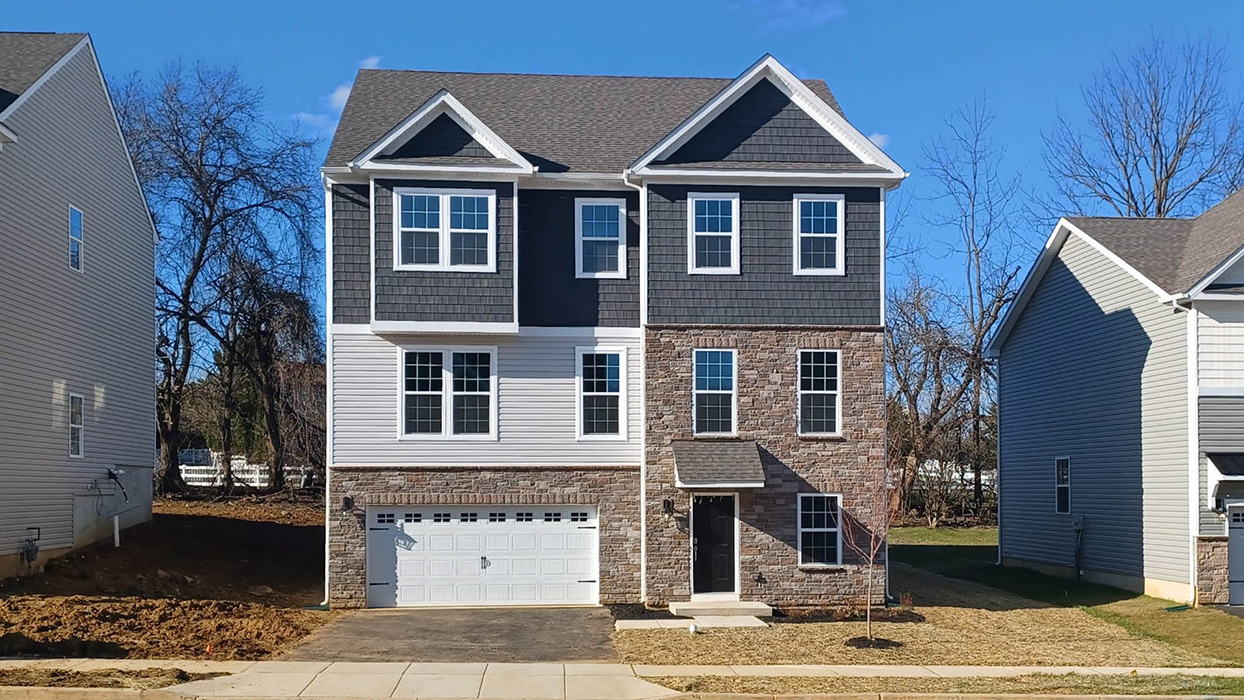 A front facing photo of a Yardley II home with sterling siding and ironstone accent siding, full ground floor stone, and a white two car garage