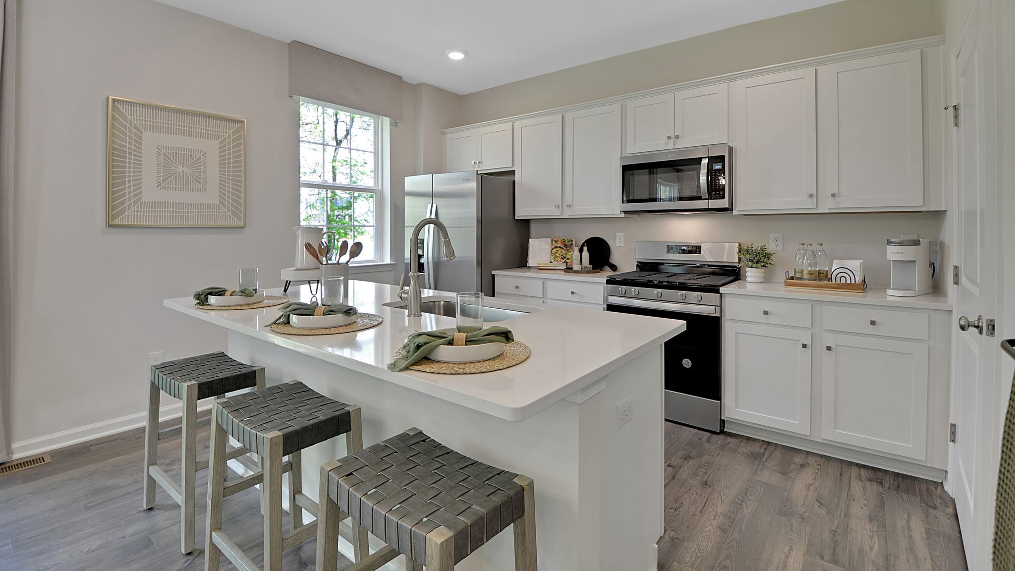 View of Kitchen with the back side of the island seating area. Stainless steel appliances with window to the left of the kitchen.