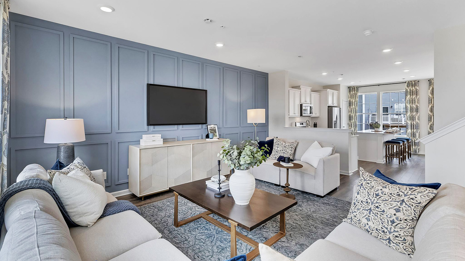 Living area with open layout view of the kitchen an stairs to the right.