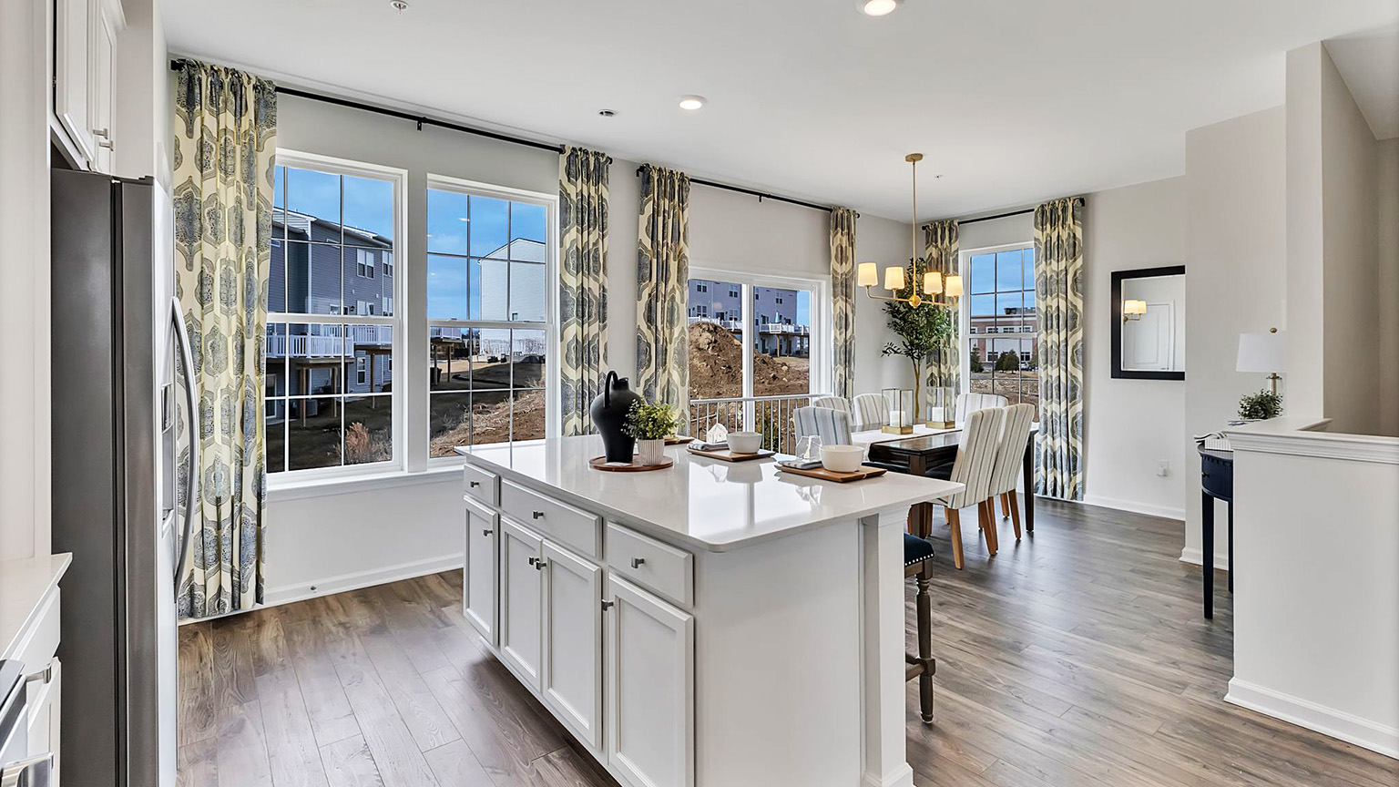 Kitchen and dining area looking into the back balcony doors and windows. View of the walkway between the kitchen counter and dining area.