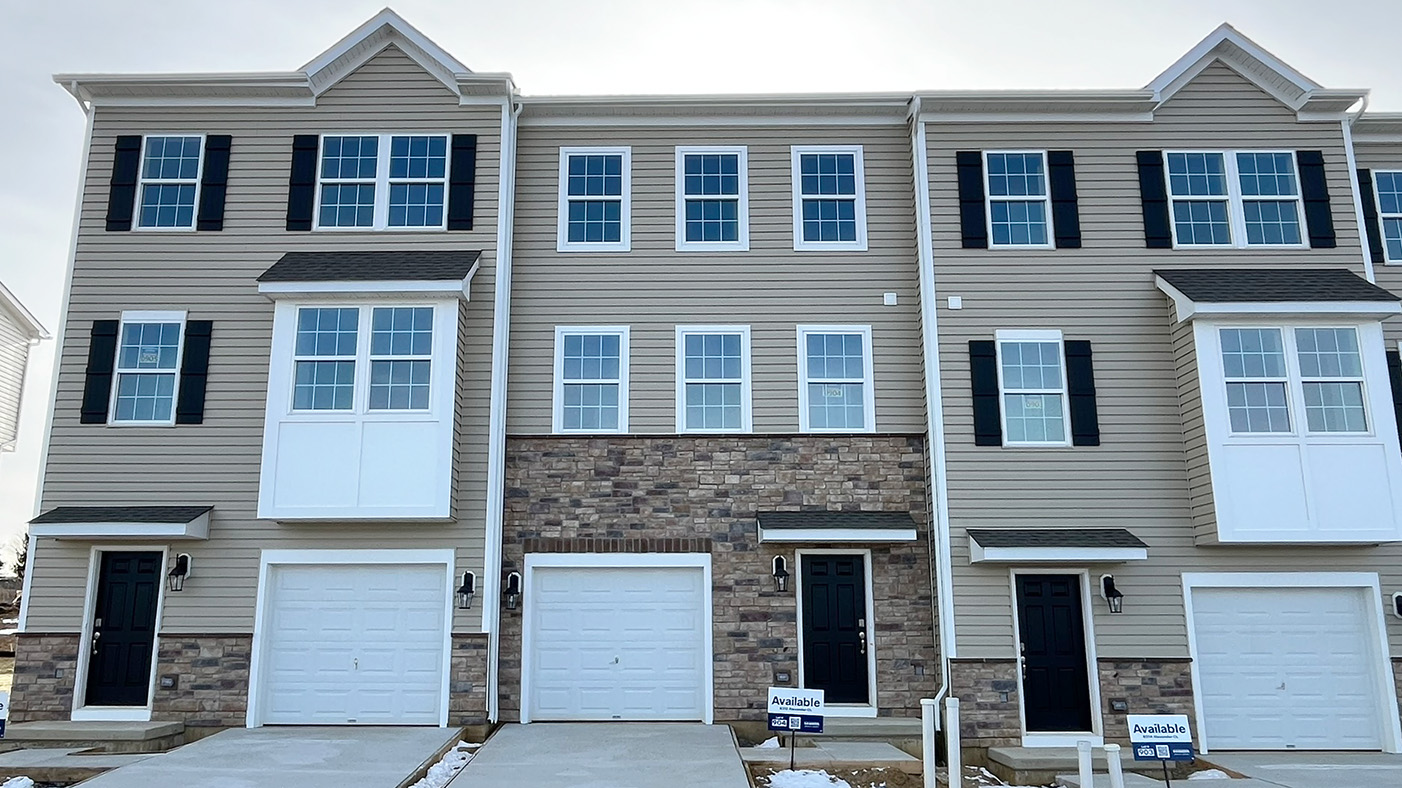 Exterior front image of the model townhome with cream horizontal panel siding and stone kneewall with white single car garage.