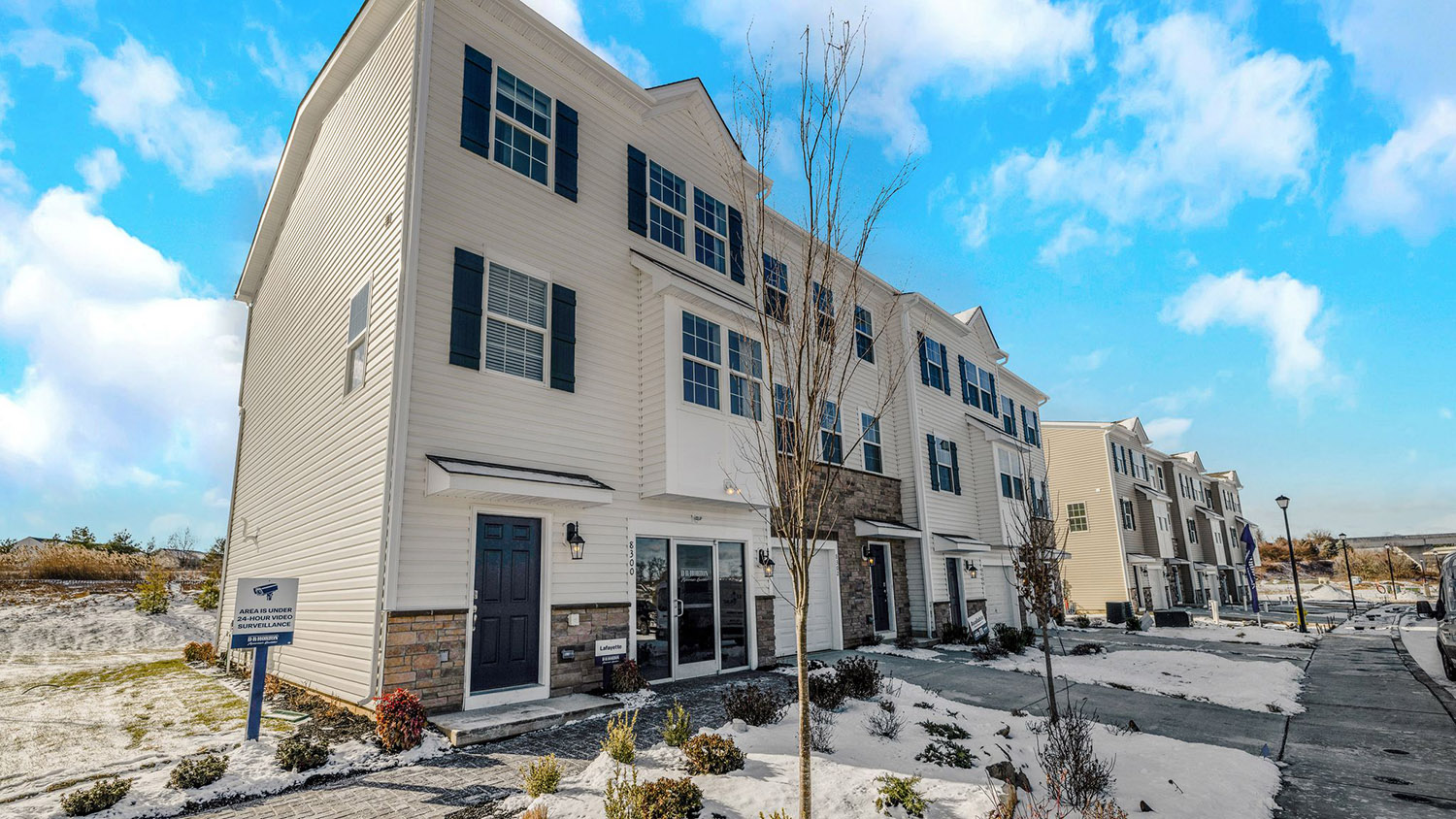 Exterior front image of the model townhome with cream horizontal panel siding and stone kneewall with white single car garage.