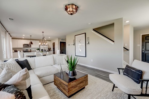 Plush sectional sofa, coffee table, and accent chair in a living room that flows into a dining area and kitchen.