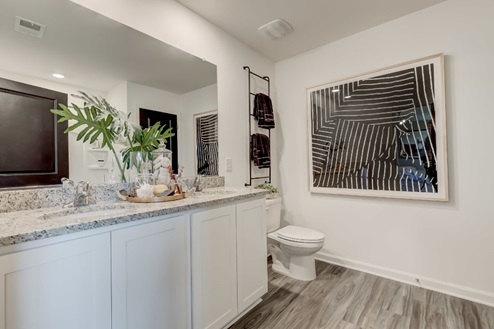 Primary bathroom with a double vanity with white, shaker-style cabinetry and quartz countertops.