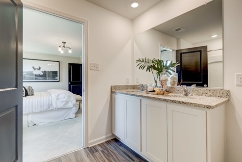 Primary bathroom with a double vanity with white, shaker-style cabinetry and quartz countertops.