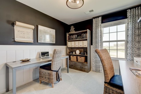 Secondary bedroom set up as an office with long desks on each wall with desk chairs and a bookshelf for added storage next to the window.