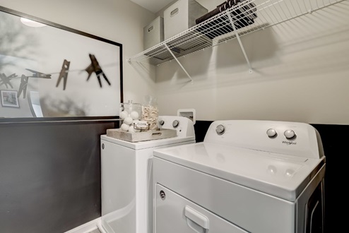 Laundry room with a side-by-side washer and dryer and shelving rack above for added storage.