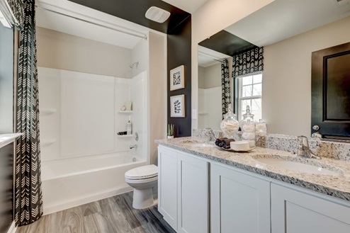 Secondary bathroom with a double vanity with white, shaker-style cabinets, quartz countertops, and a tub-shower combo.