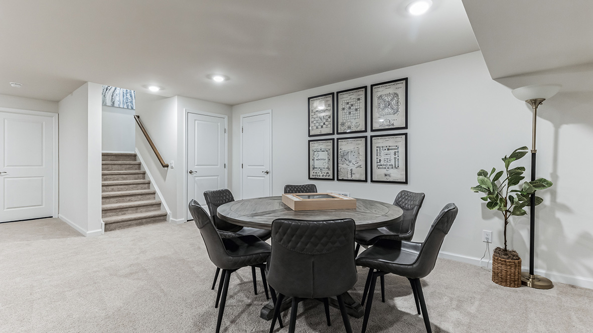 Different view of the finished basement or recreation room area with stairs and three doors to different rooms in the basement.