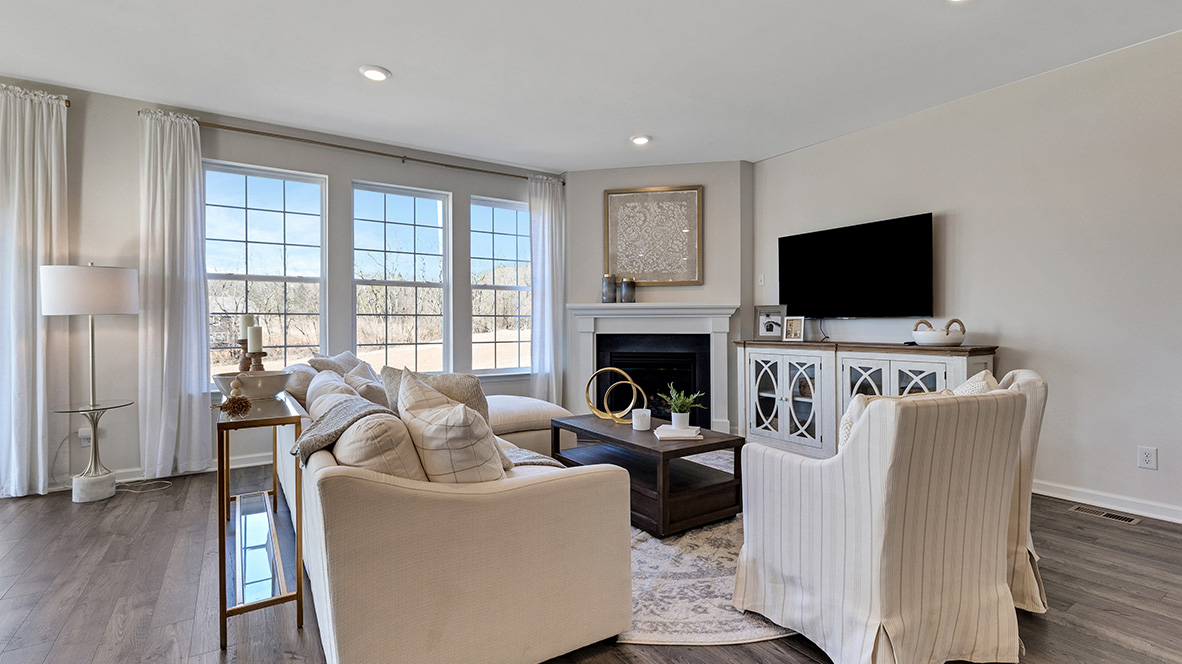 Living area and three large single windows next to the fireplace.