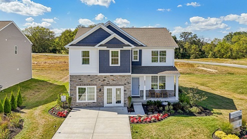 An aerial rear view of a two-story home with blue and cream siding with partial stone.
