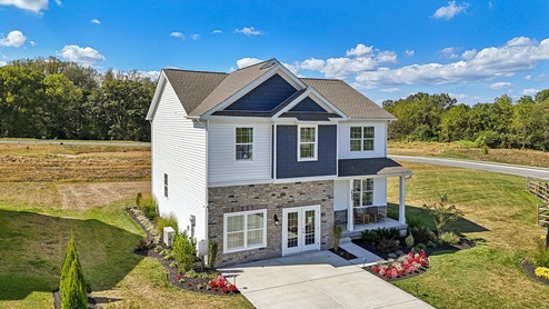An aerial rear view of a two-story home with blue and cream siding with partial stone.