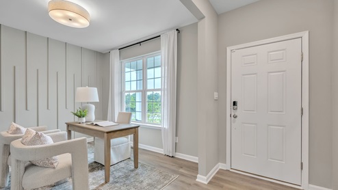 Front entry room with tan wood flooring and textured accent wall.