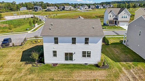 An aerial rear view of a two-story home with white horizontal plank siding