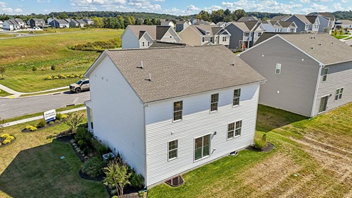 An aerial rear view of a two-story home with white horizontal plank siding