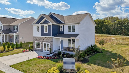 An aerial rear view of a two-story home with blue and cream siding with partial stone.