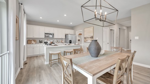 Open concept kitchen and dining area with white cabinetry and light wood flooring.