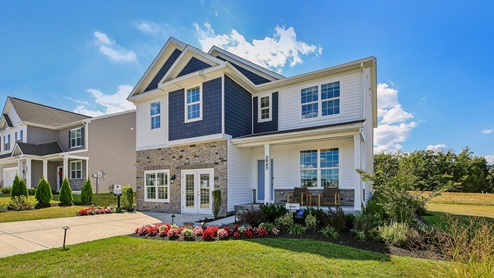 Exterior of the home with blue and cream siding with partial stone.