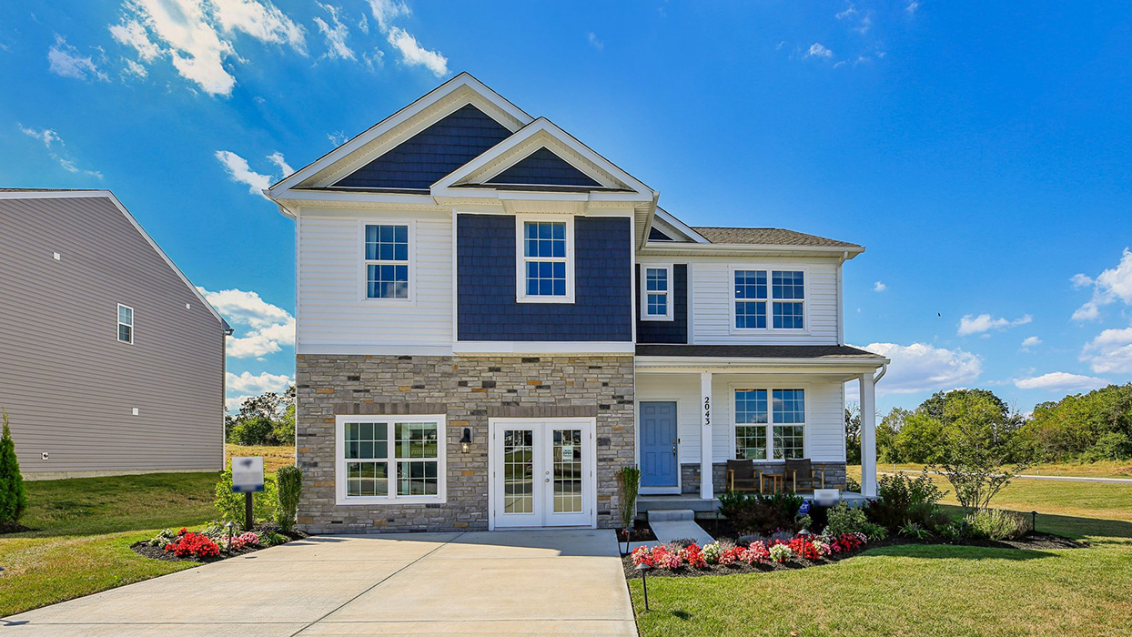 Exterior of the home with blue and cream siding with partial stone.