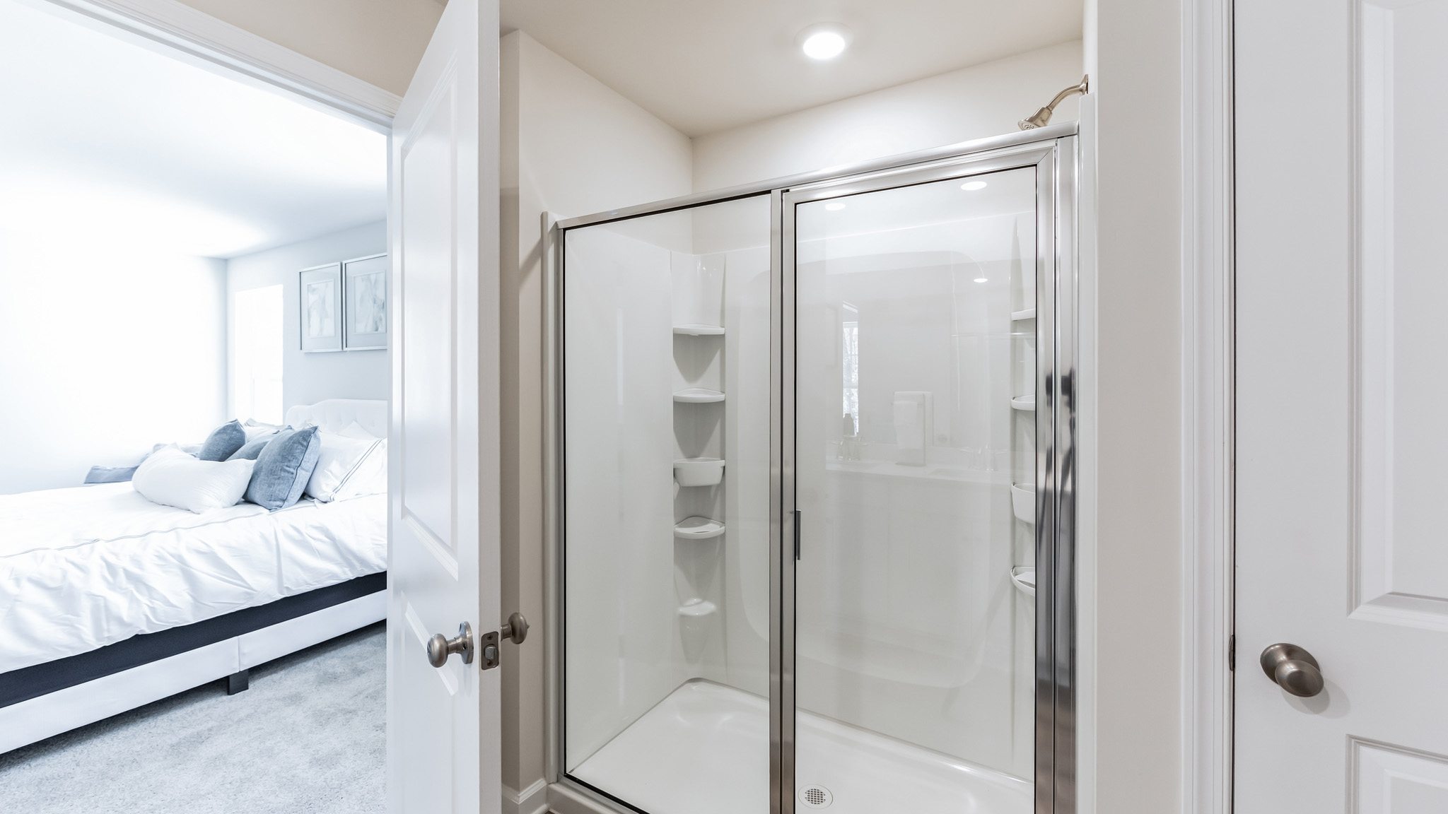 The primary bathroom with shower and view back into the primary bedroom.