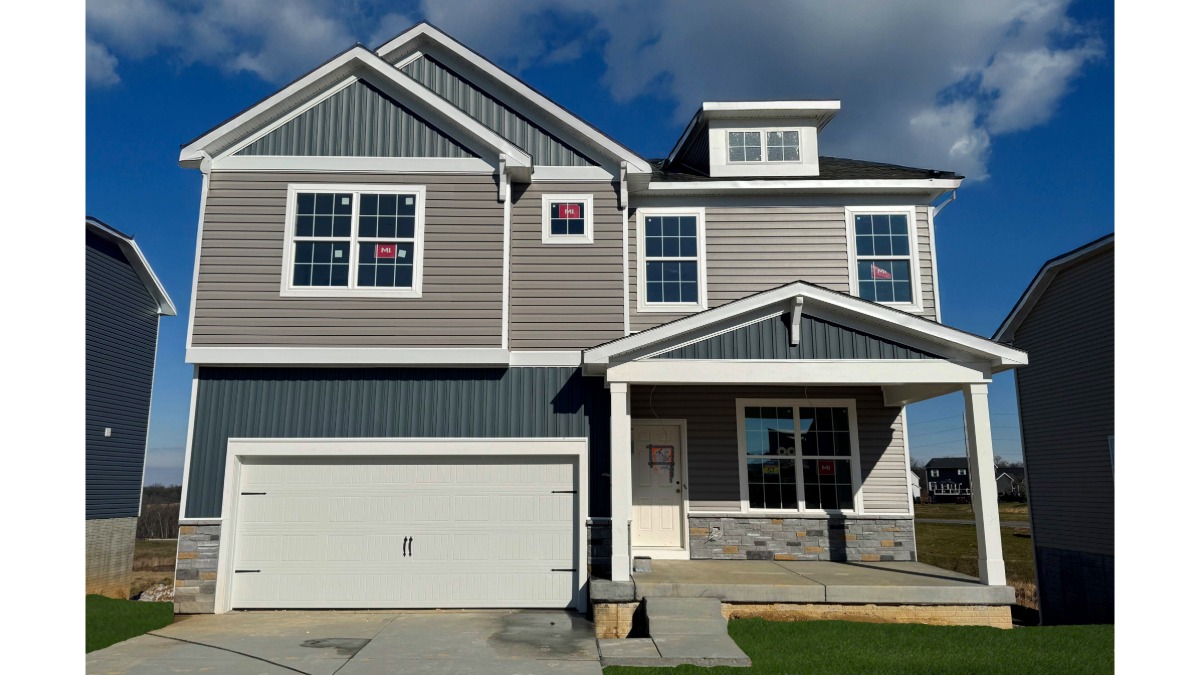 A photo of a two-story Penwell home with gray and tan siding, stone kneewall, and a white two car garage.