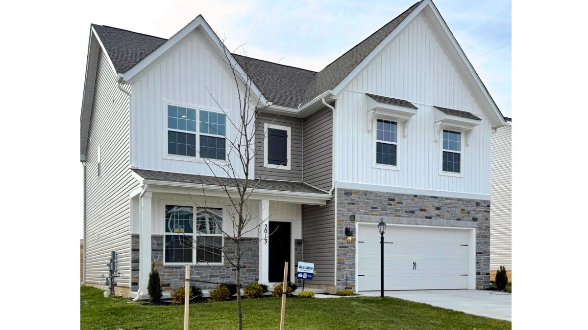 A photo of a two-story Henley home with white and stone siding surrounding a white two car garage.