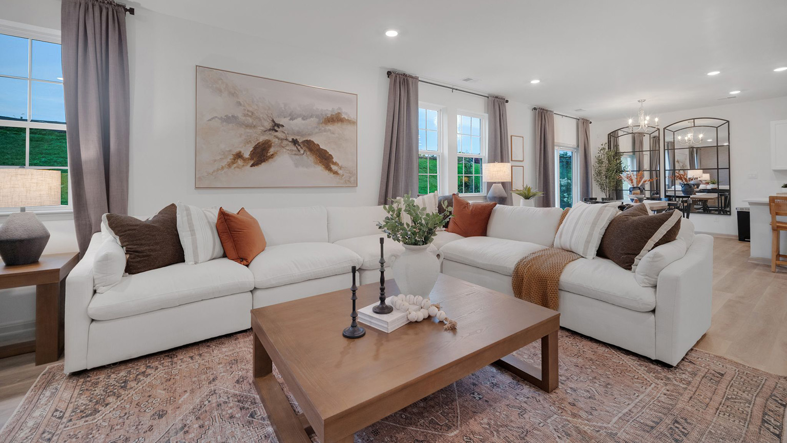 Living room with a large sectional sofa and coffee table in front of a wall boasting three windows and a set of sliding glass doors overlooking the back yard.