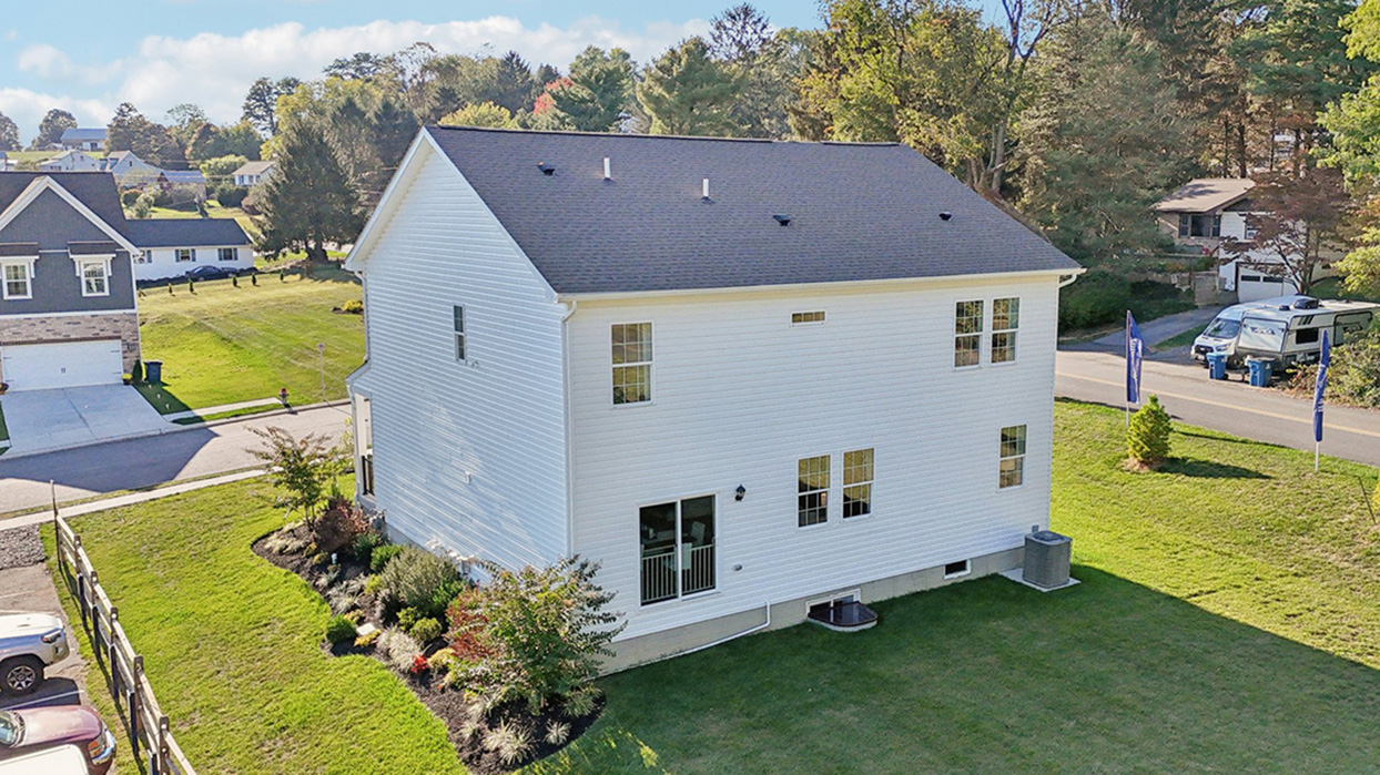 An elevated rear view of two story home with blue and white siding with brick.