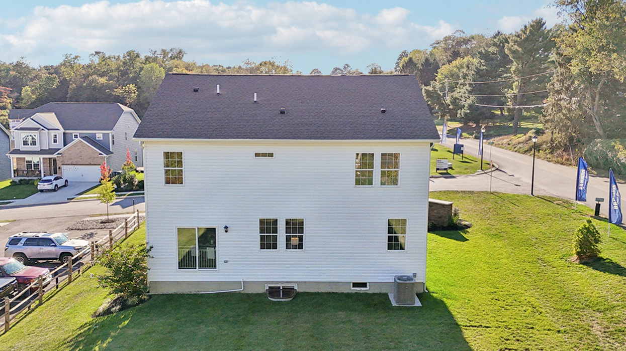 An elevated rear view of two story home with blue and white siding with brick.