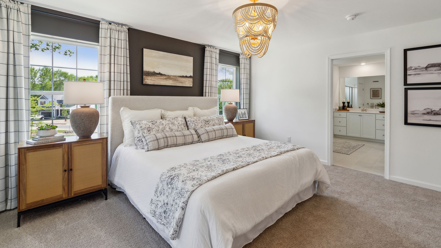 Primary bedroom has two large single windows on either side of the bed and a connecting large full bath with two double sink white vanities.