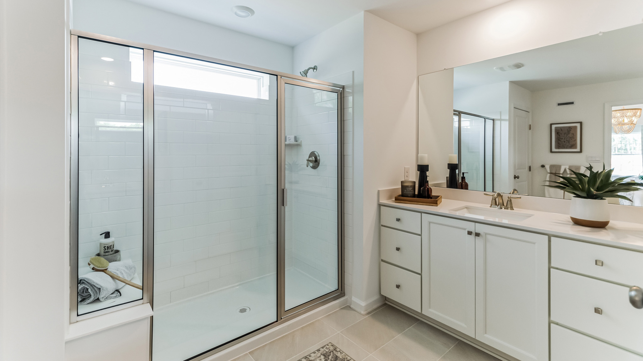 Primary bathroom with large glass door shower and sitting bench inside.