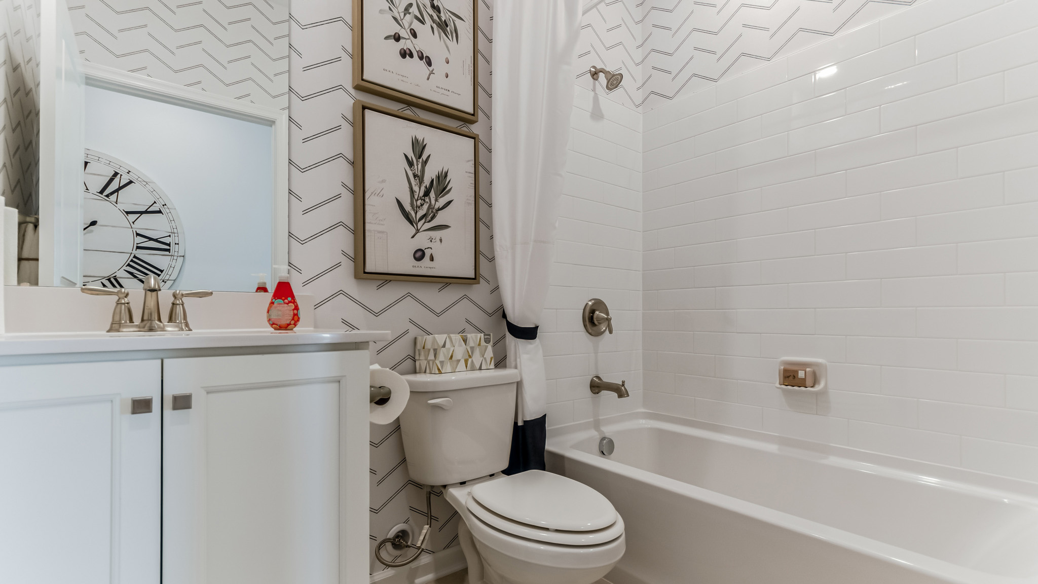 Full bath with a white single sink vanity next to the entryway storage nook.