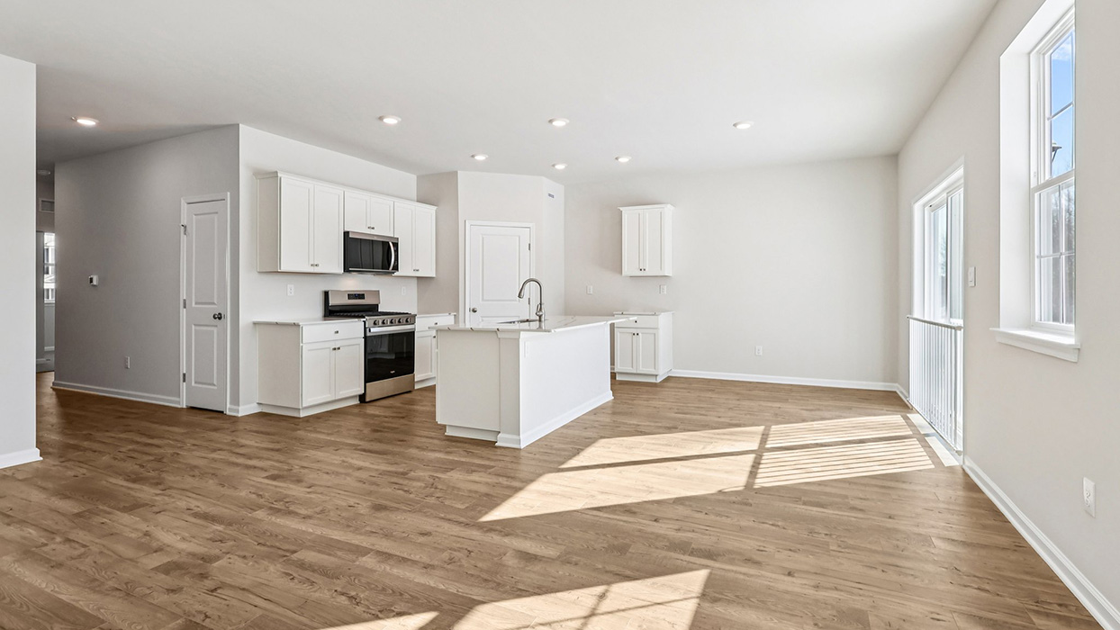 A wide angle view of the open concept living area, kitchen, and dining in the back right corner