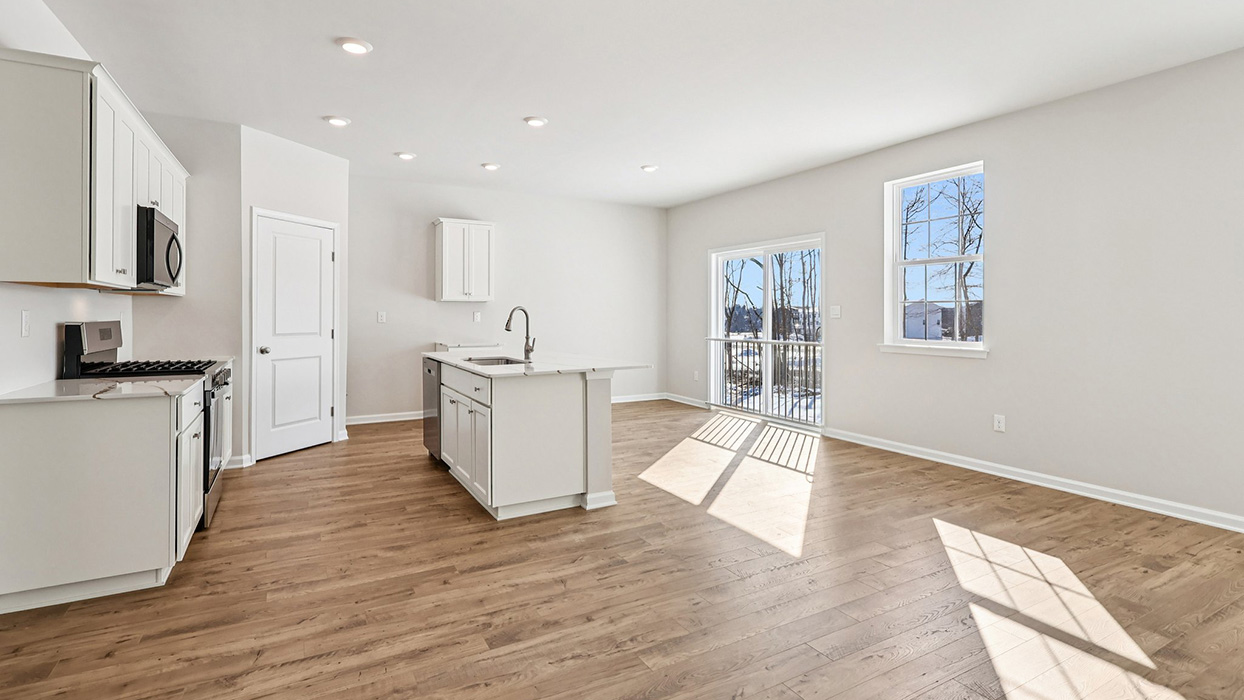A different wide angle view of the kitchen area, large island, and dining in the back right corner